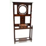 A 1920s oak hall stand with barley twist uprights and trinket drawer and twin apertures for