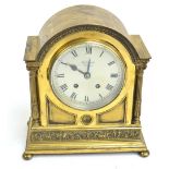 A brass arched top mantel clock with two fluted Corinthian columns, a frieze of cherubs,