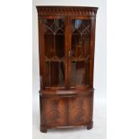 A reproduction mahogany free standing corner cupboard with twin glazed upper doors,