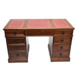 A reproduction oak pedestal desk with tooled red leather top with central drawer flanked by four