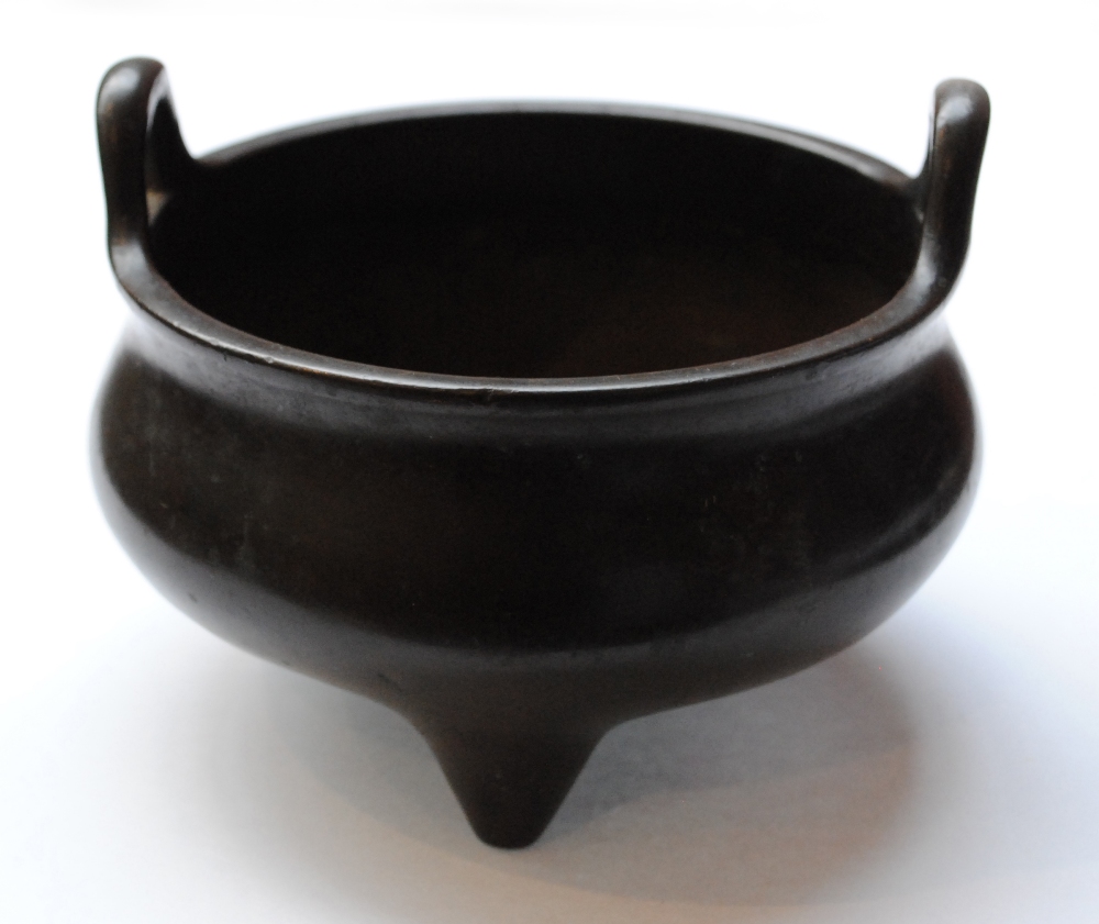 A Chinese bronze twin handled circular censer on three supports,