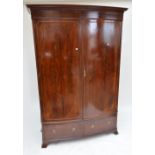 An Edwardian mahogany slightly bow front wardrobe with two hinged doors with oval crossbanded