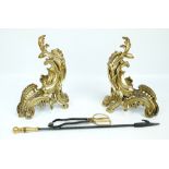 A pair of brass Rococo style foliate scroll decorated hand irons,