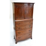 A reproduction mahogany slightly bowfronted tallboy with cornice above two hinged doors enclosing a