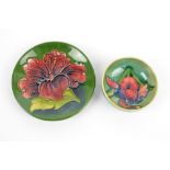 MOORCROFT; a 'Hibiscus' pattern tube line decorated circular plate on green ground,