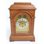 An early 20th oak and inlaid Junghans bracket clock with arched dial,