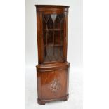 A reproduction mahogany freestanding corner cupboard with glazed upper section and floral painted