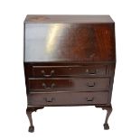 A reproduction mahogany bureau with fitted interior, three long drawers and cabriole legs,