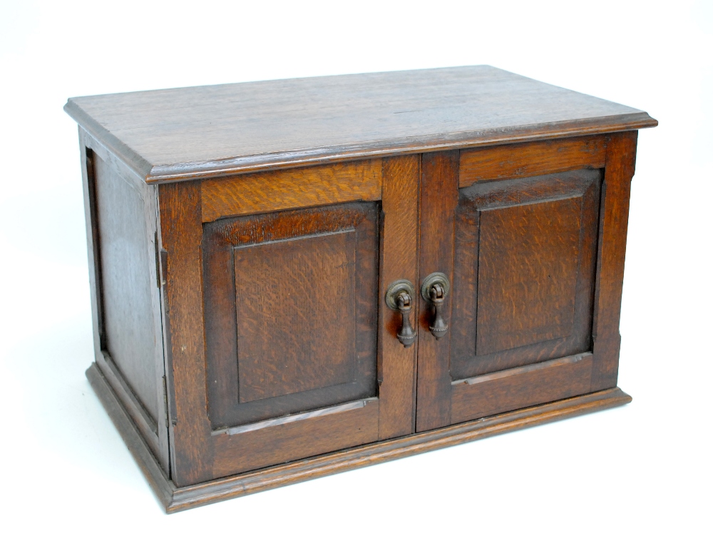 A 1920s oak two door cabinet with moulded plinth, width 55cm.