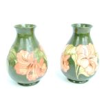 MOORCROFT; a pair of baluster vases in the 'Hibiscus' pattern on a green ground,