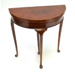 An early 20th century walnut demi-lune card table raised on cabriole legs to pad feet, width 69cm.