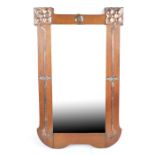 An Arts and Crafts mahogany and copper clad wall mirror of shaped rectangular form with bevelled