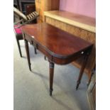 An early 19th century mahogany fold-over tea table with rounded rectangular top and ring turned