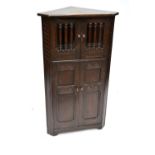 A reproduction oak corner cupboard with twin glazed upper doors and twin panel lower doors by