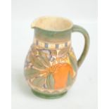 CHARLOTTE RHEAD BURSLEY WARE; a pipe lined jug with green ground with fruit and floral decoration,