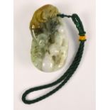 A 20th century Chinese three tone jade pebble carved with stylised ram and sheep amongst foliage,