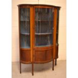 An Edwardian inlaid mahogany serpentine-shaped display cabinet with glazed bow-fronted central door