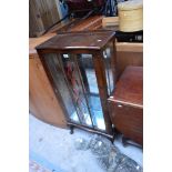 A mid-20th century display cabinet with single glazed door, central decorative panel,