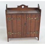 An oak Arts and Crafts smoker's cabinet with decorative copper hinges to the two doors,