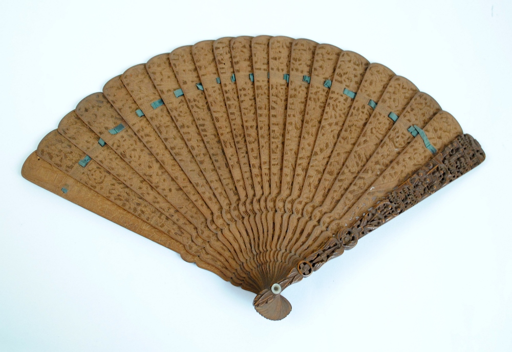 An early 20th century Chinese carved sandalwood brisé fan decorated with figural and architectural