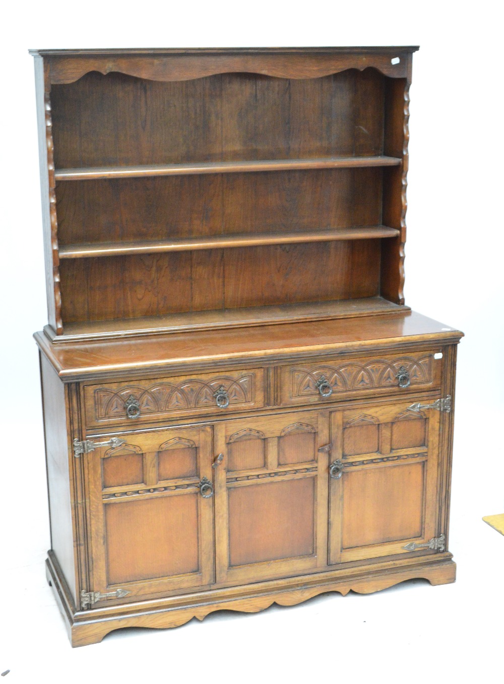 A reproduction oak dresser with boarded plate rack and carved detail.