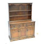 A reproduction oak dresser with boarded plate rack and carved detail.