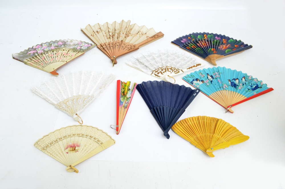 A collection of decorative fans including folding wood and paper examples, a yellow bamboo example,