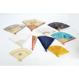 A collection of decorative fans including folding wood and paper examples, a yellow bamboo example,