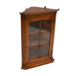 ANDREW KIDD; a reproduction oak glazed hanging corner cupboard with moulded cornice.