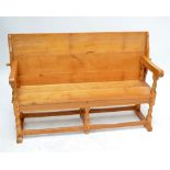 A large light oak monk's bench with sliding back, plank seat and turned and block supports,