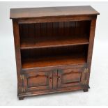 A reproduction oak open shelved bookcase with twin fielded panel cupboard doors to the lower