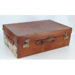 An early 20th century leather suitcase with old travel stickers to include British India Steam