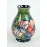 MOORCROFT; a single 'Anemone' pattern tube line decorated baluster vase on a green ground,