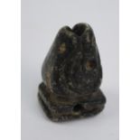 A small pre-Colombian carved stone stylised head with pierced holes to the rounded square section