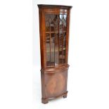 A reproduction mahogany serpentine outlined freestanding corner cupboard.