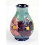 MOORCROFT; a 'Clematis' pattern tube line decorated baluster vase on blue ground,