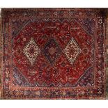 A Persian designed rug with three lozenge shaped medallions within an all over red/blue gound main