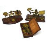 Two sets of brass letter weights and an oak-cased set of scales for silver and gold (3).