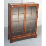 An Edwardian mahogany two-door glazed bookcase with three shelves, raised on bracket supports,