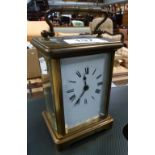 A French carriage clock in lacquered brass, enamelled dial set with Roman numerals.