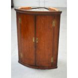 A late George III oak two-door wall-hanging bow-fronted corner cupboard with H-shaped brass hinges,