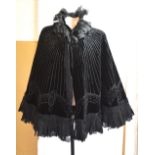 A Victorian black velvet evening cape with silk ruffle collar and hem and decorative panels of