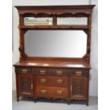 A late Victorian mahogany dresser with mirrored back and carved cornice,