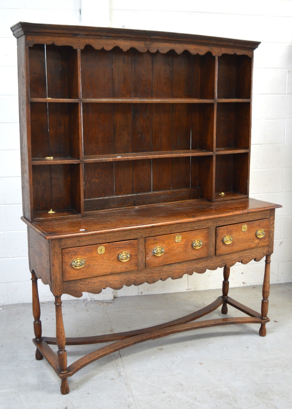 An early 19th century oak dresser, the boarded plate rack above three frieze drawers,