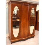 An Edwardian mahogany inlaid triple-door wardrobe with central bow-front panel and two mirrored