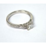 An 18ct white gold three-diamond ring, central square-cut stone set between brilliant-cut stones,