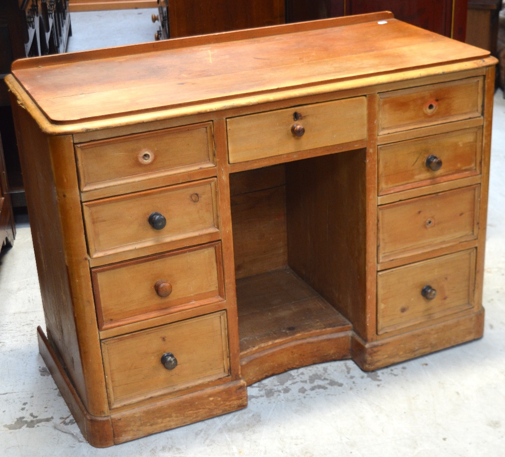 A Victorian pine kneehole desk with upstand, central drawer flanked by two banks of four drawers,