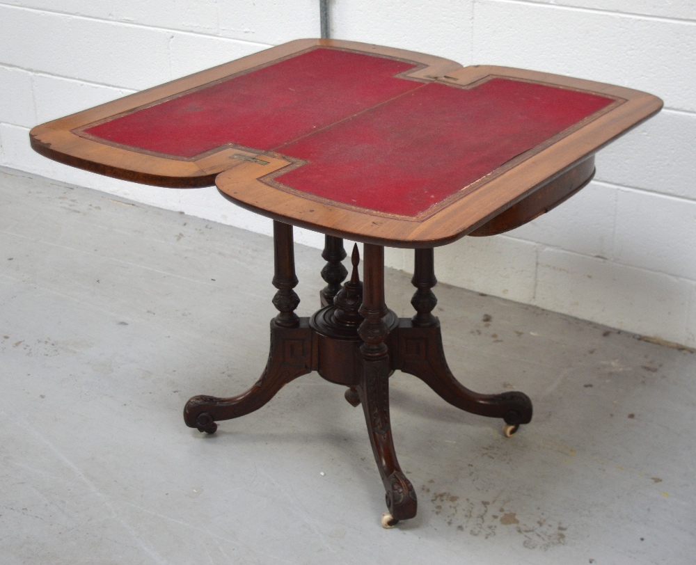 A 19th century mahogany fold-over games table on turned tapering supports to quatrefoil carves base,