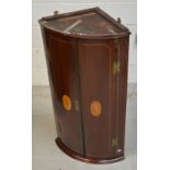 A late 19th century mahogany curved-front corner cabinet with two marquetry inlaid doors with brass