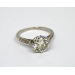 A platinum ring set with an antique-cut round solitaire diamond, with diamond-set shoulders,